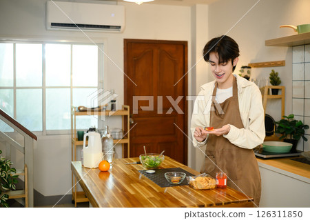 Young man enjoying homemade snack in cozy kitchen Young man enjoying homemade snack in cozy kitchen 126311850
