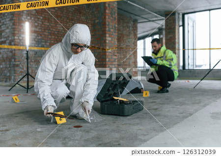 At daytime. Detectives are collecting evidence in a crime scene near dead body 126312039