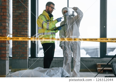 At daytime. Detectives are collecting evidence in a crime scene near dead body At daytime. Detectives are collecting evidence in a crime scene near dead body 126312044