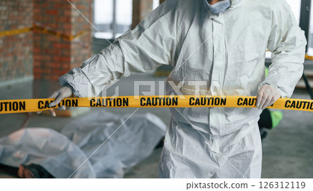 Holding caution police tape. Detectives are collecting evidence in a crime scene near dead body 126312119