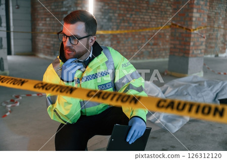 Sitting near caution police tape. Detectives are collecting evidence in a crime scene with dead body 126312120