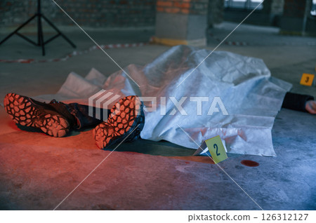 Dead body of a man is on the ground, covered in white cloth. Conception of murder, homicide 126312127