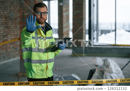 Stop gesture by a hand, no trespassing. Detectives are collecting evidence in a crime scene near dead body Stop gesture by a hand, no trespassing. Detectives are collecting evidence in a crime scene near dead body 126312132