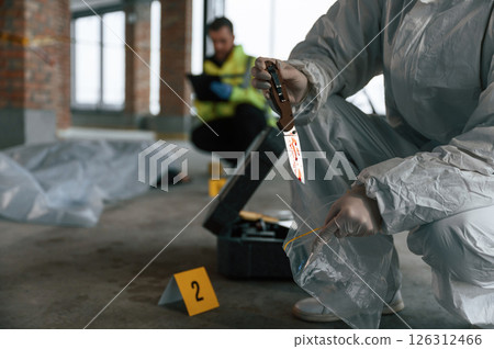 Putting the knife into bag. Detectives are collecting evidence in a crime scene near dead body Putting the knife into bag. Detectives are collecting evidence in a crime scene near dead body 126312466