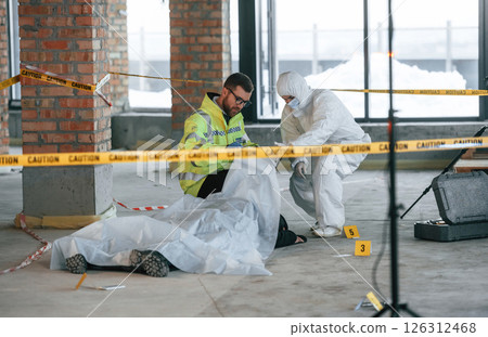 At daytime. Detectives are collecting evidence in a crime scene near dead body 126312468