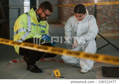 Sitting and laughing. Two detectives are collecting evidence in a crime scene. Forensic specialists are making expertise 126312477