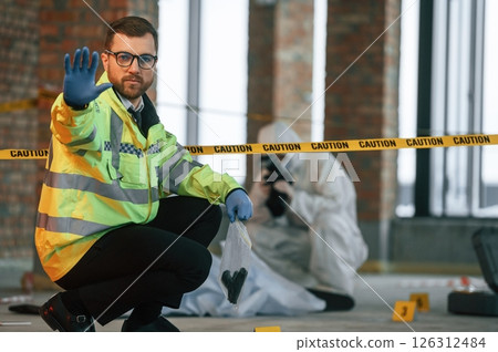 Dead body is on the ground. Detectives are collecting evidence in a crime scene 126312484