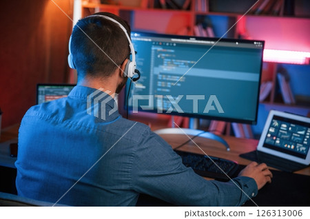 Professional programmer is working indoors. Neon lighting Professional programmer is working indoors. Neon lighting 126313006