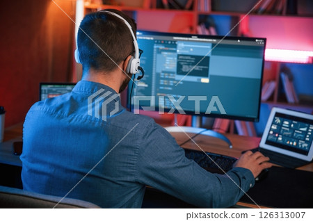 Professional programmer is working indoors. Neon lighting 126313007