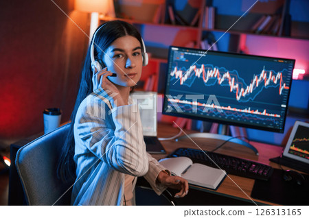Looking into the camera. Female stock trader is working by pc indoors. Conception of exchange and money 126313165