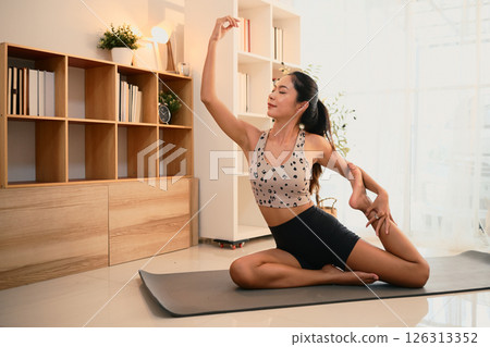 Beautiful asian woman practicing elegant yoga stretches in a peaceful living room 126313352