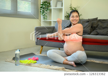 Healthy pregnancy with home exercise showing dedication to wellness and self-care 126313362
