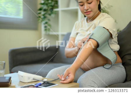 Pregnant woman checks her blood pressure at home. Maternal wellness and health care concept 126313371