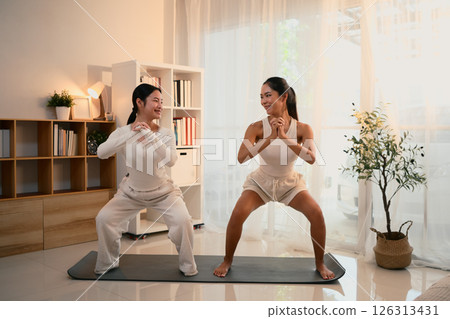 Asian mom and her teen daughter doing yoga workout at home Asian mom and her teen daughter doing yoga workout at home 126313431