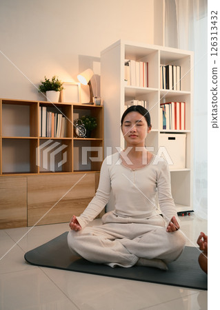 Teenage asian girl meditating in a calm and cozy home environment Teenage asian girl meditating in a calm and cozy home environment 126313432