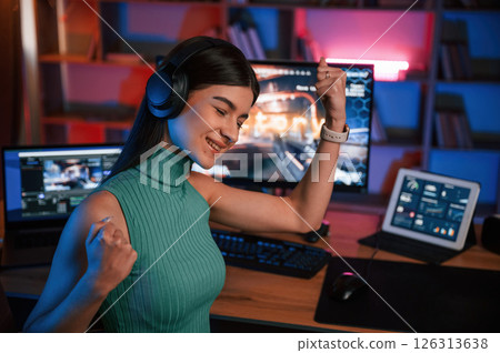 Portrait of young pretty female gamer that is playing shooter. Neon lighting Portrait of young pretty female gamer that is playing shooter. Neon lighting 126313638