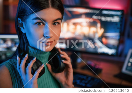 Portrait of young pretty female gamer that is playing shooter. Neon lighting 126313640