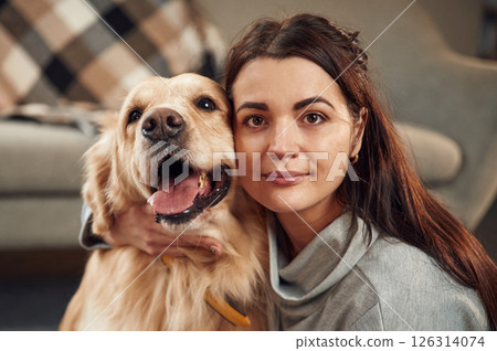 Looking at the camera. Woman is with golden retriever dog at home Looking at the camera. Woman is with golden retriever dog at home 126314074