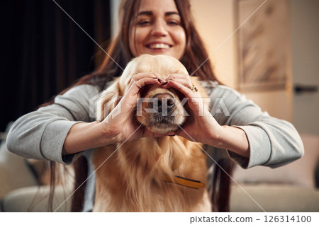 Covering face with hands. Love gesture. Woman is with golden retriever dog at home 126314100