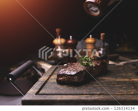 Chef adding salt and thyme to grilled steak Chef adding salt and thyme to grilled steak 126314134
