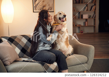 Sitting on the sofa. Woman is with golden retriever dog at home Sitting on the sofa. Woman is with golden retriever dog at home 126314212