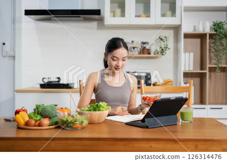 Fit woman enjoys healthy fresh vegetables and fruits breakfast sitting in the kitchen. Fit woman enjoys healthy fresh vegetables and fruits breakfast sitting in the kitchen. 126314476
