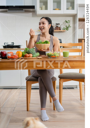 Fit woman enjoys healthy fresh vegetables and fruits breakfast sitting in the kitchen. Fit woman enjoys healthy fresh vegetables and fruits breakfast sitting in the kitchen. 126314494