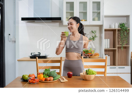 Fit woman enjoys healthy fresh vegetables and fruits breakfast sitting in the kitchen. Fit woman enjoys healthy fresh vegetables and fruits breakfast sitting in the kitchen. 126314499