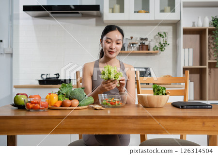 Fit woman enjoys healthy fresh vegetables and fruits breakfast sitting in the kitchen. Fit woman enjoys healthy fresh vegetables and fruits breakfast sitting in the kitchen. 126314504