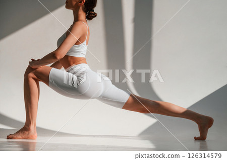 Young caucasian woman with slim body shape is indoors in the studio. Fitness exercises Young caucasian woman with slim body shape is indoors in the studio. Fitness exercises 126314579