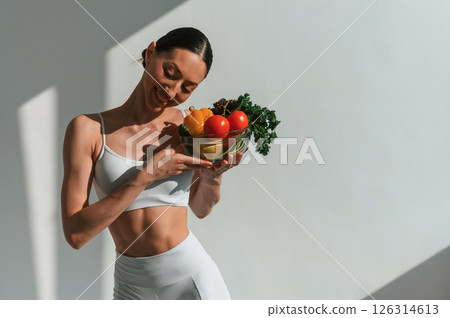 Healthy food. With fruits and vegetables. Young caucasian woman with slim body shape is indoors in the studio 126314613