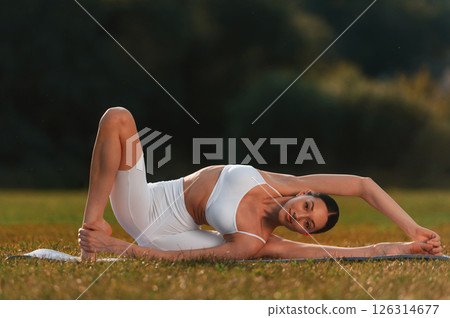 Yoga practice on the mat. Young caucasian woman with slim body shape is in the fitness clothes outdoors 126314677