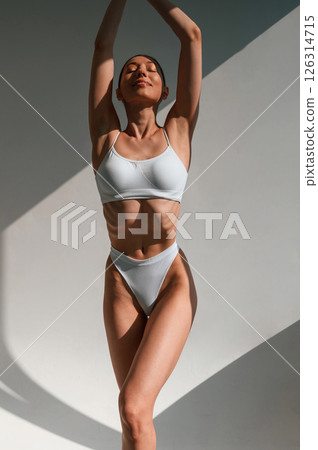 Front view. Standing and posing. Young caucasian woman with slim body shape is indoors in the studio Front view. Standing and posing. Young caucasian woman with slim body shape is indoors in the studio 126314715