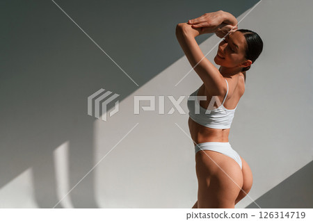 Showing the back. Young caucasian woman with slim body shape is indoors in the studio Showing the back. Young caucasian woman with slim body shape is indoors in the studio 126314719