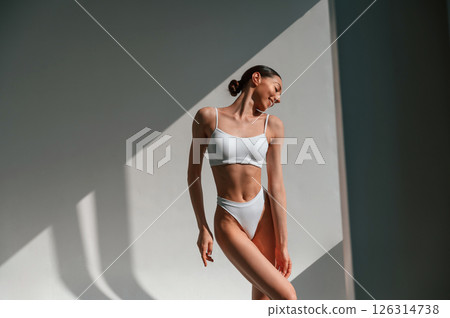 Illuminated by sunlight. Young caucasian woman with slim body shape is indoors in the studio 126314738