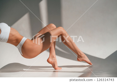 On the legs and hands. Close up view. Young caucasian woman with slim body shape is indoors in the studio 126314743