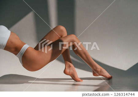 On the legs and hands. Close up view. Young caucasian woman with slim body shape is indoors in the studio On the legs and hands. Close up view. Young caucasian woman with slim body shape is indoors in the studio 126314744