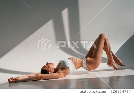 Relaxed, taking a rest. Lying down on a floor. Young caucasian woman with slim body shape is indoors in the studio 126314784