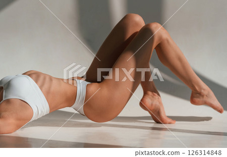 On the floor. View of legs and fitness body type. Young caucasian woman is indoors in the studio On the floor. View of legs and fitness body type. Young caucasian woman is indoors in the studio 126314848