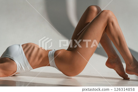 On the floor. Close up view. Young caucasian woman with slim body shape is indoors in the studio 126314858
