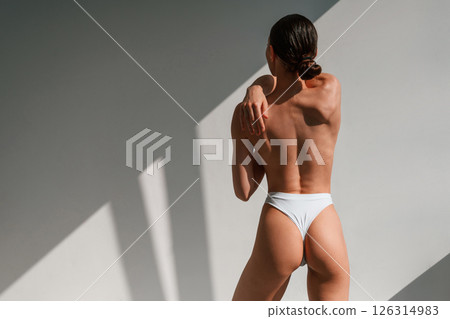View from the back. Young caucasian woman with slim body shape is indoors in the studio 126314983