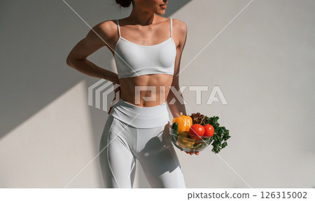 Conception of healthy eating. With fruits. Young caucasian woman with slim body shape is indoors in the studio Conception of healthy eating. With fruits. Young caucasian woman with slim body shape is indoors in the studio 126315002