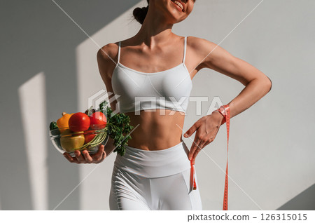 Conception of diet. With vegetalbes and fruits. Young caucasian woman with slim body shape is indoors in the studio 126315015
