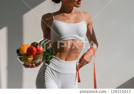 Conception of diet. With vegetalbes and fruits. Young caucasian woman with slim body shape is indoors in the studio Conception of diet. With vegetalbes and fruits. Young caucasian woman with slim body shape is indoors in the studio 126315017