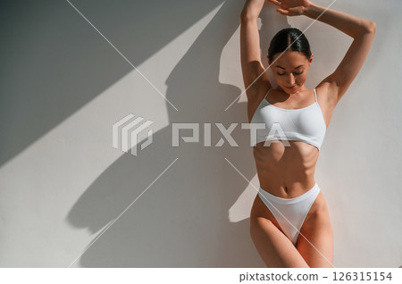 Leaning on the wall. Young caucasian woman with slim body shape is indoors in the studio Leaning on the wall. Young caucasian woman with slim body shape is indoors in the studio 126315154