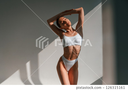 Front view. Standing and posing. Young caucasian woman with slim body shape is indoors in the studio Front view. Standing and posing. Young caucasian woman with slim body shape is indoors in the studio 126315161