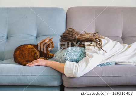 Woman with Dreadlocks Sleeping on Sofa with Cat Relaxing Next to Her. Woman with Dreadlocks Sleeping on Sofa with Cat Relaxing Next to Her. 126315498