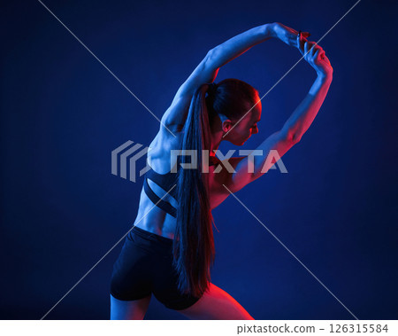 Beautiful muscular woman is indoors in the studio with neon lighting 126315584