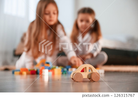 With toys on the floor. Two little girls are playing and having fun together in domestic room With toys on the floor. Two little girls are playing and having fun together in domestic room 126315767