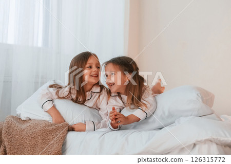 Lying down on the bed. Two little girls are playing and having fun together in domestic room 126315772